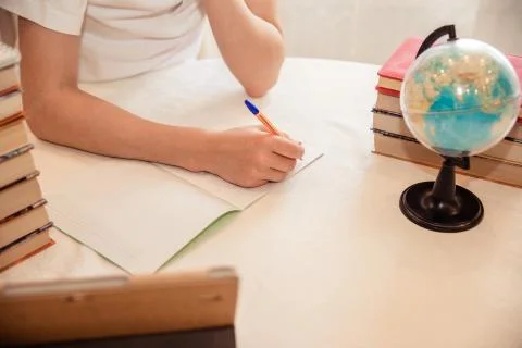 A boy schoolboy does his homework. Textbooks and notebooks on the table Stock Photos