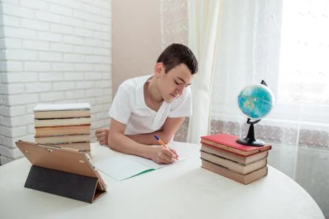 A boy schoolboy does his homework. Textbooks and notebooks on the table Stock Photos