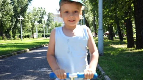 Boy on scooter in park Stockbeeldmateriaal 115121275