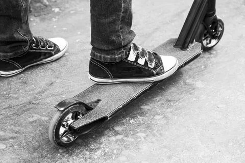 A boy on a scooter in a skate park performs jumps and tricks Foto stock