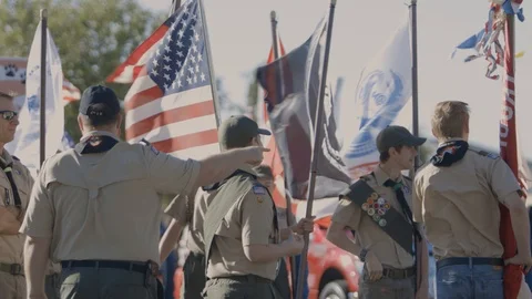 Boy Scout marching in a parade with an American flag Stock Footage 100004822
