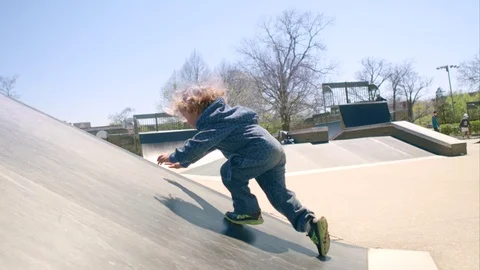Boy scrambles on a slippery slope and falls Stock-Footage 75998927