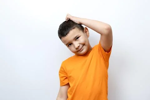 A boy is scratching his head while standing on a white background in an ora.. Foto stock