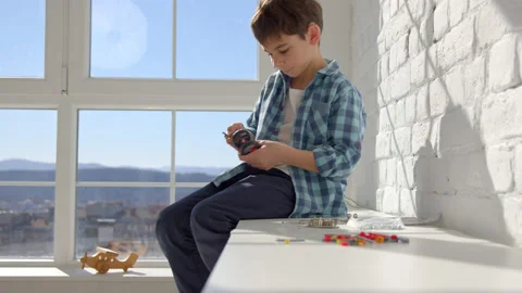 Boy with the screwdriver assembling a robot sitting at home. 4k slow motion Stock Footage 171092466