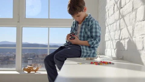 Boy with the screwdriver assembling a robot sitting at home. 4k slow motion Stock Footage 171092659