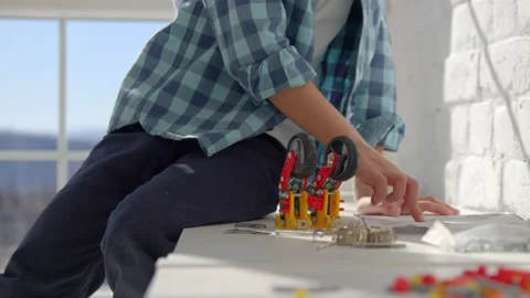 Boy with the screwdriver assembling a robot sitting at home. 4k slow motion Stock Footage 171092757