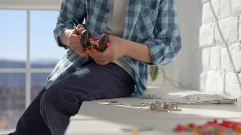 Boy with the screwdriver assembling a robot sitting at home. 4k slow motion Stock Footage 171092925
