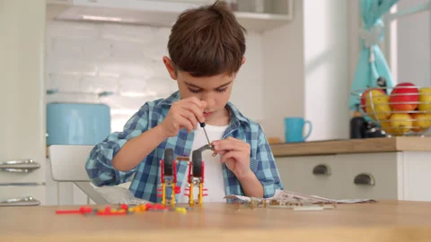 Boy with the screwdriver assembling a robot sitting at home. 4k slow motion Stock Footage 171092969