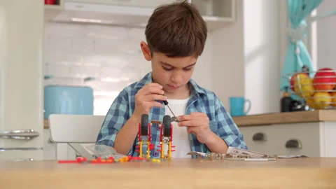 Boy with the screwdriver assembling a robot sitting at home. 4k slow motion Stock Footage 171093246