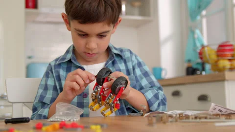 Boy with the screwdriver assembling a robot sitting at home. 4k slow motion Stock Footage 171093664