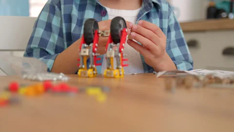 Boy with the screwdriver assembling a robot sitting at home. 4k slow motion Stock Footage 171093883