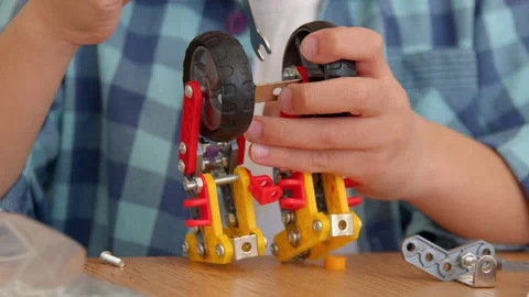 Boy with the screwdriver assembling a robot sitting at home. 4k slow motion Stock Footage 171093948