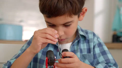 Boy with the screwdriver assembling a robot sitting at home. 4k slow motion Stock Footage 171094084