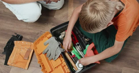 Boy searches toolbox to find suitable screwdriver for father Stockbeeldmateriaal 323968749