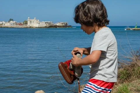 Boy on the seashore preparing his camera Stock Photos