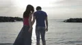 a boy on the seashore at sunset hugs her girlfriend and jokes with water HD Footage