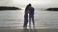 a boy on the seashore at sunset hugs her girlfriend and jokes with fake kiss HD Footage
