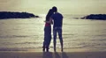 a boy on the seashore at sunset hugs her girlfriend and jokes with fake kiss HD Footage