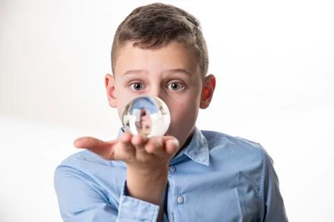 Boy sees his mirror image in a glass ball directly in front of his face again Stock Photos