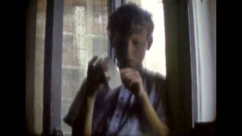 Boy setting alarm clock in bright room. Teenage boy holding mechanical watch Stock Footage 269965158