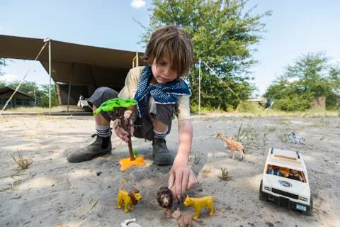 A boy setting up a safari scene with toy jeeps and wild animal toys and a tall Stock Photos