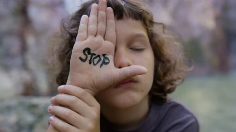 The boy shielded his eye with his hand on which the inscription stop is written Stock Footage 191469884