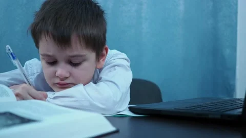 A boy in a shirt writes with a pen in a notebook. deleted items Stock Footage 144263305