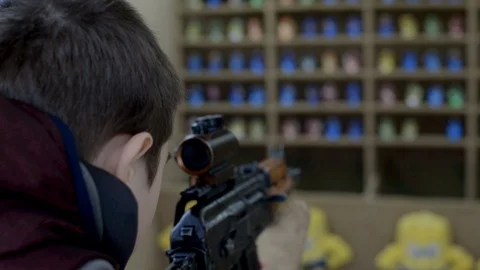 Boy in shooting range aims at the can,shoots with a rifle and hits the target Stock Footage 128242143