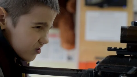 A boy in a shooting range aims from a rifle at a target, close-up Stock Footage 128242312