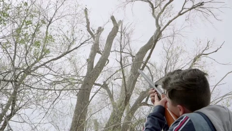 Boy shoots at a bird with a bb gun in a remote area outside during wintertime. Video stock 169733281