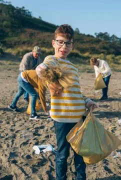 Boy showing doll head while cleaning the beach Stock Photos