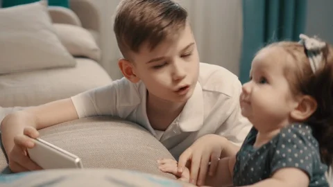 Boy showing smartphone screen younger sister at home Stock Footage 104079855