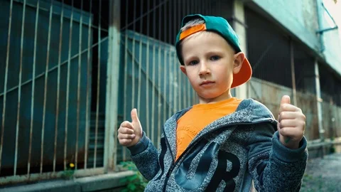 Boy shows class with thumbs up posing on camera standing in a backstreet Stock-Footage 89133166