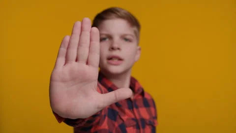 Boy Shows Palm at Camera Saying Wait on Yellow Background Stock Footage 316684051