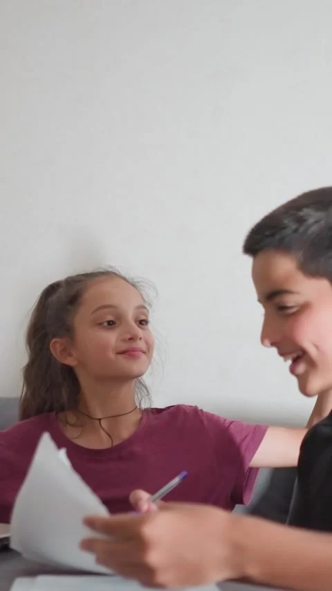 Boy shows written work to friend who playfully slaps his head in reaction Stock Footage 320354498