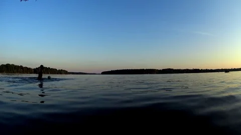 Boy silhouette have fun, play with ball in lake water, summer sunset Stock Footage 74951489
