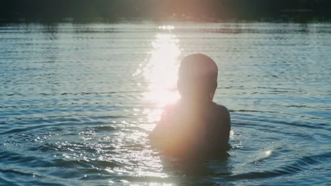 Boy Silhouette Rising From Lake Surface at Sunset Stock Footage 344689361
