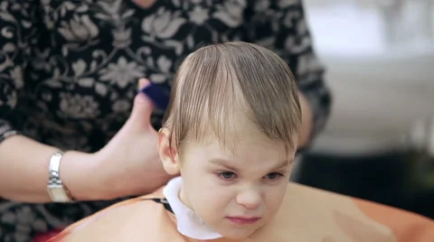 Boy sings while barber cuts his hair Stock Footage 49396106