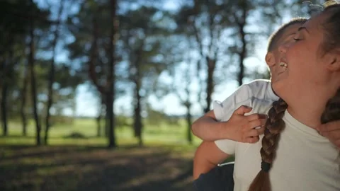Boy on sister back smiling wide. Girl holds brother close walking forest path Stock Footage 346239967