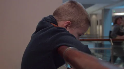 Boy Sits and Misses at the Mall, While His Parents Make Purchase Stock Footage 61069399