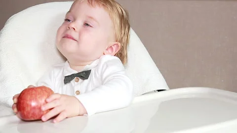 A boy sits with an Apple at the table Stock Footage 138698686