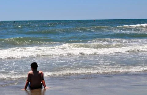 Boy sits on beach Stockfoto's