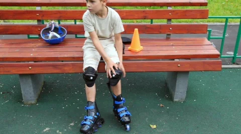 Boy sits on bench in rollers standing and dresses protection Stock Footage 714922