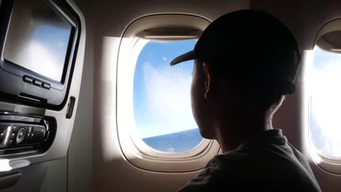 The boy sits in the cabin of the plane and looks out the window. Stock Footage 277688686