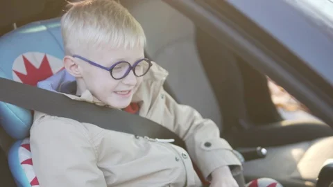 The boy sits in the car in the car seat. He buckled. Stock Footage 96991816