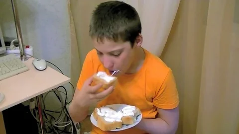 The boy sits on a chair and eats bread with sour cream Stock Footage 74759338