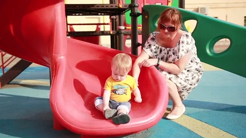 A boy sits on a childrens slide Stock Footage 133120137
