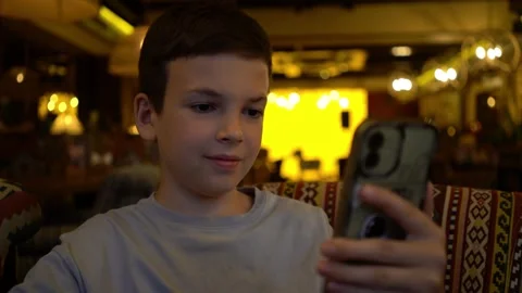 Boy sits in cozy cafe using smartphone for social media  Video stock 342193738