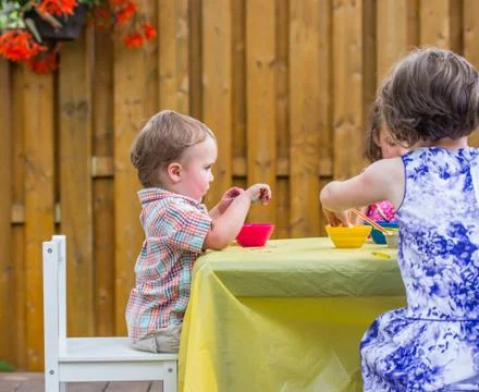 Boy Sits Dyeing Easter Eggs Together with Children Stock Photos