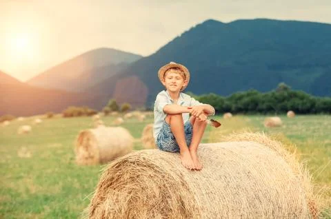 Boy sits on the haystack top Foto stock